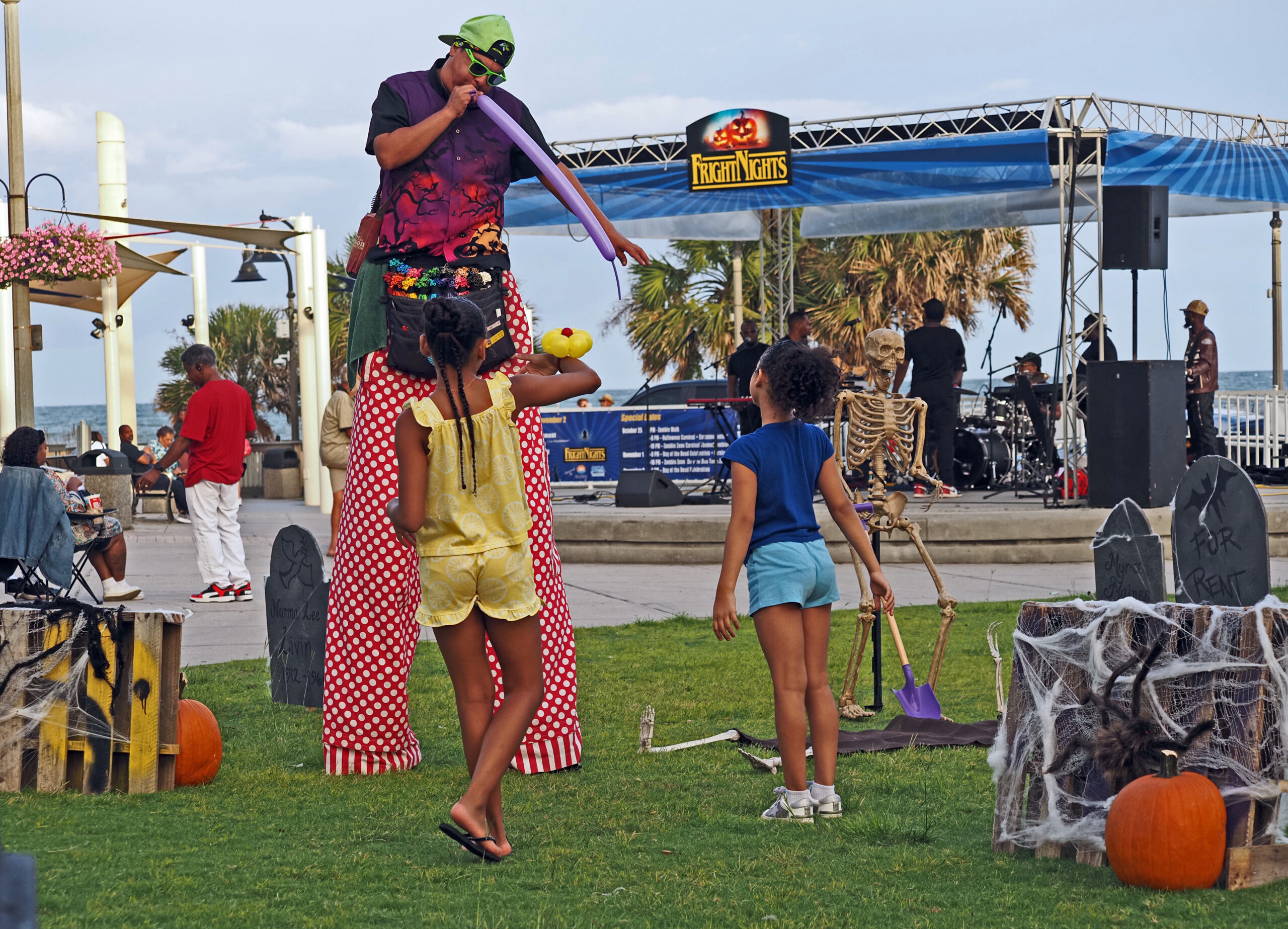 Stilt walker making balloon animals for two children at Fright Nights, one of the free Halloween events in downtown Myrtle Beach